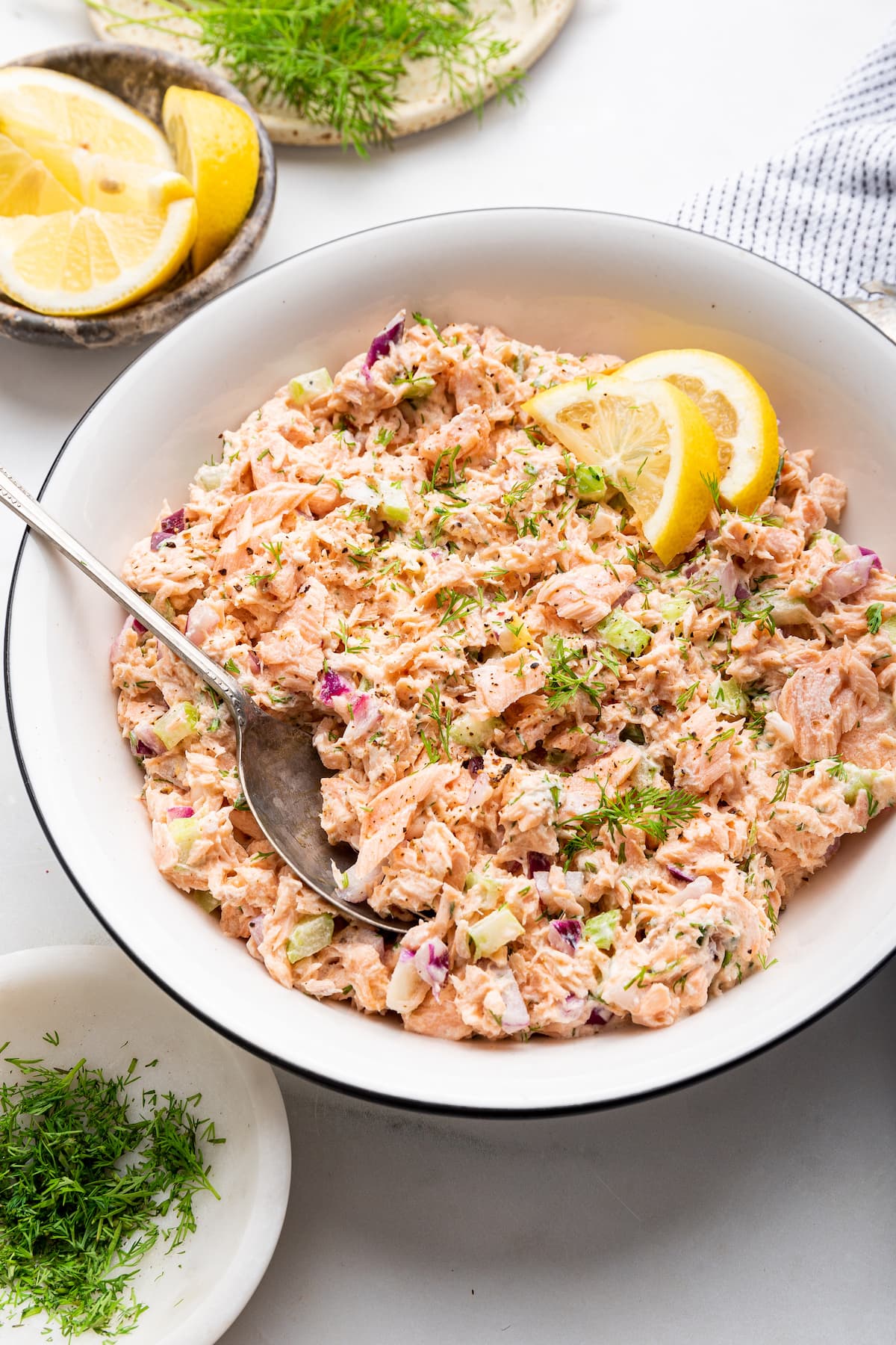 Salmon salad in a white bowl with a serving spoon.