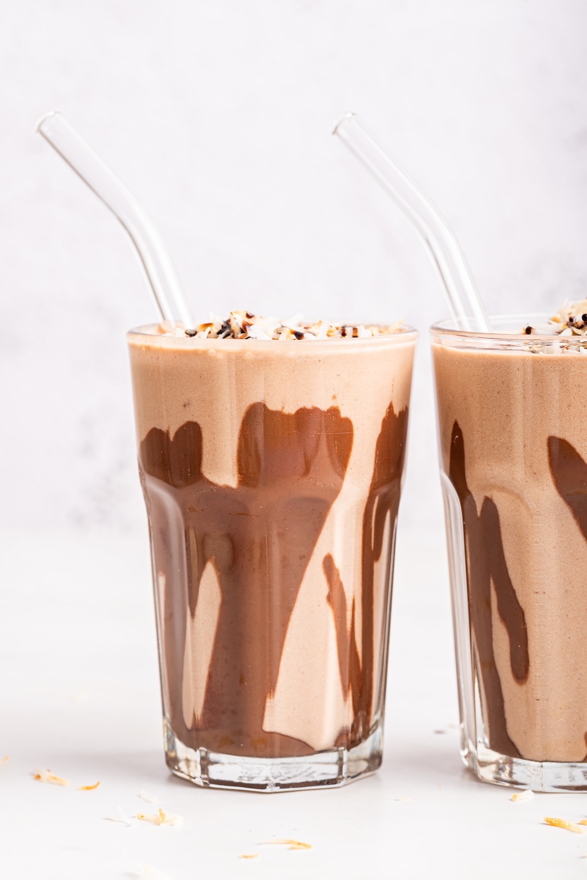 A samoa cookie protein shake in a glass that has drizzled chocolate around the sides.