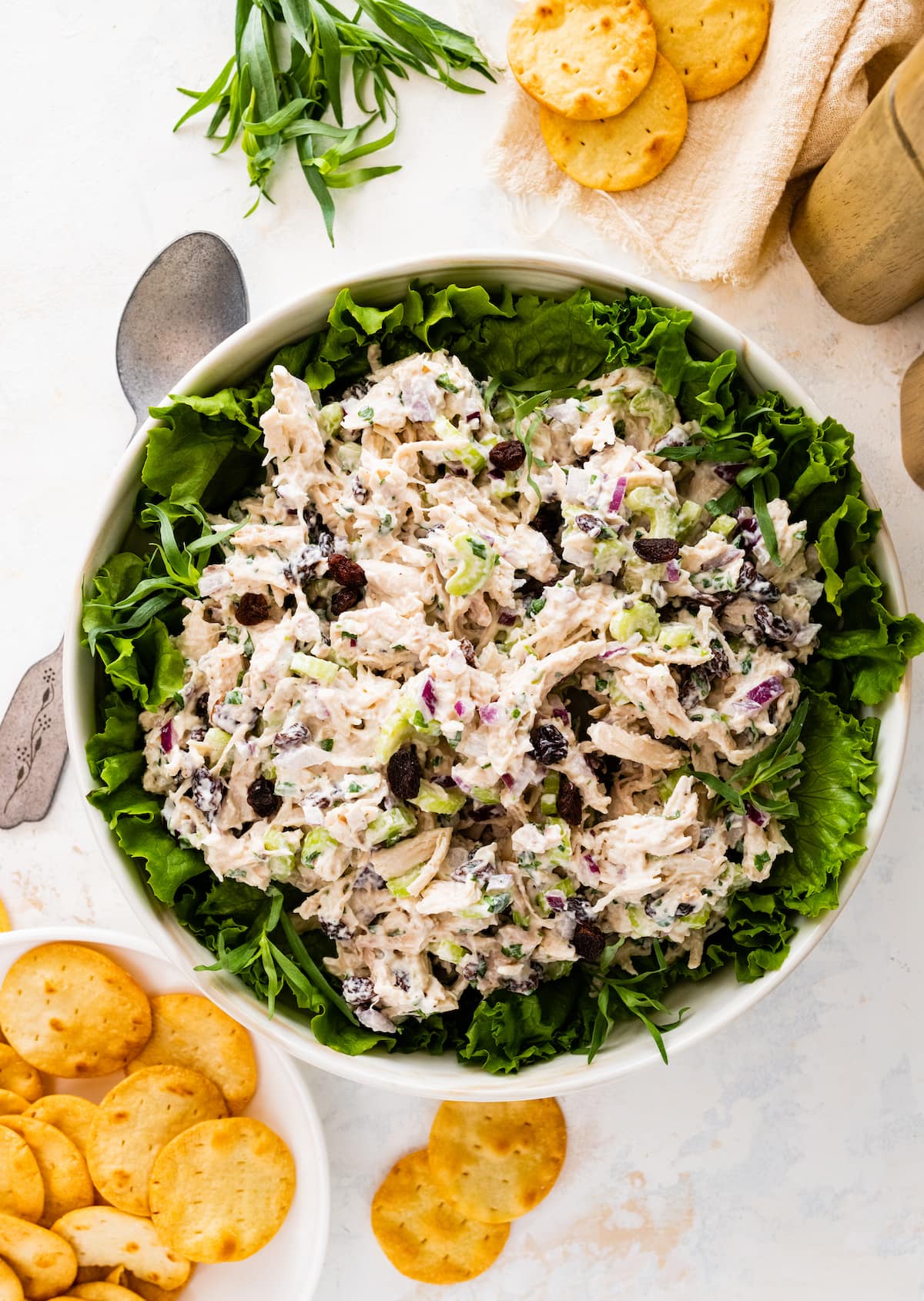 Tarragon chicken salad in a white serving bowl served on top of a bed of greens.