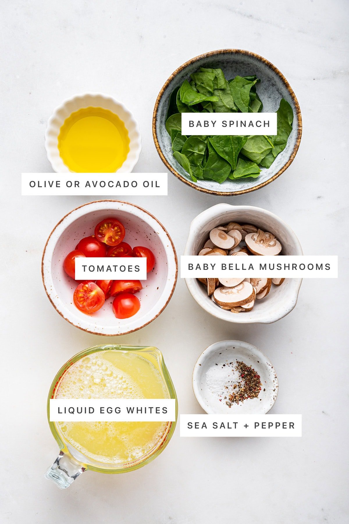 Ingredients measured out to make Scrambled Egg Whites: olive oil, baby spinach, tomatoes, baby belle mushrooms, liquid egg whites, sea salt and pepper.