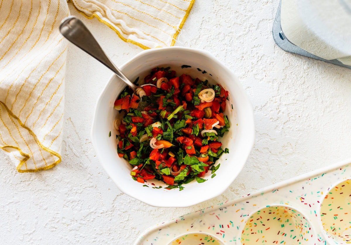 A mix of chopped red pepper, onion, and spinach in a small bowl.
