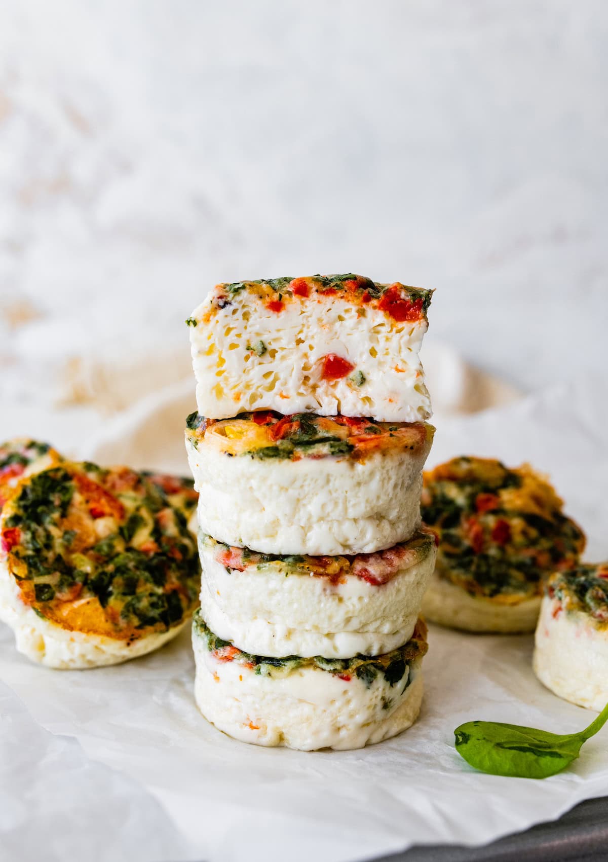 Four egg white bites stacked on one another with a bite taken from the top one.