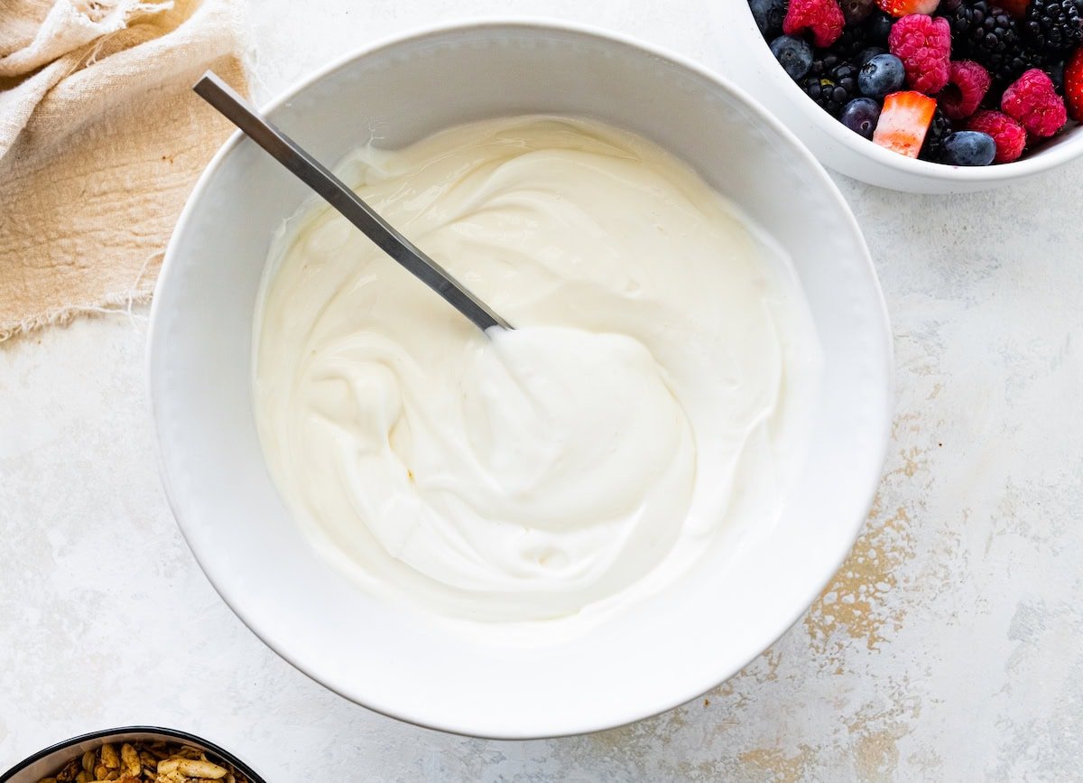 A large bowl of yogurt with a metal spoon.