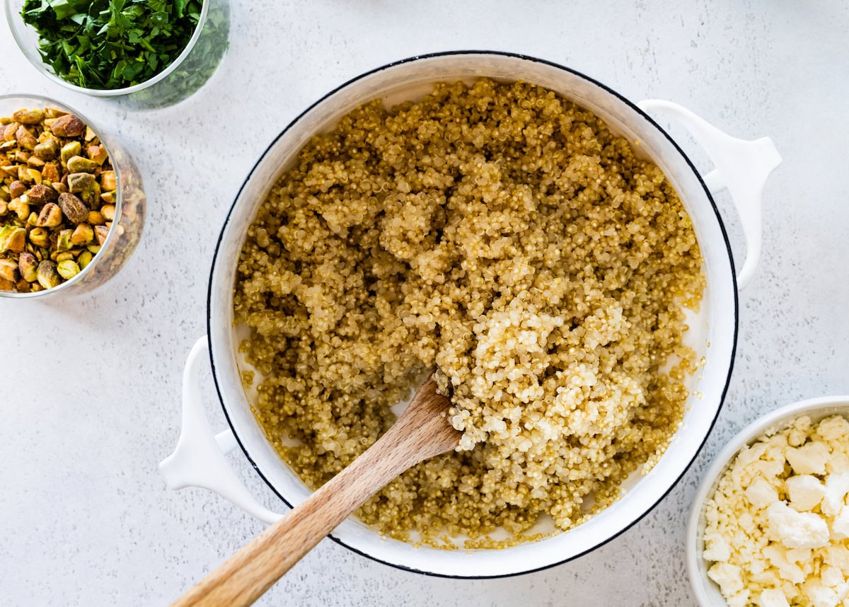 A large pot of cooked quinoa with a wooden spoon.