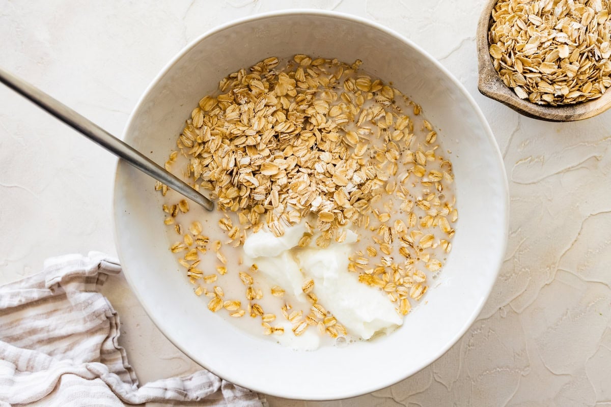 Rolled oats in a large mixing bowl of milk and yogurt.
