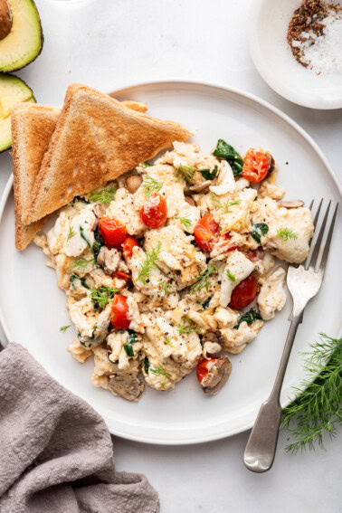 Scrambled egg whites on a plate with two pieces of toast on the side.