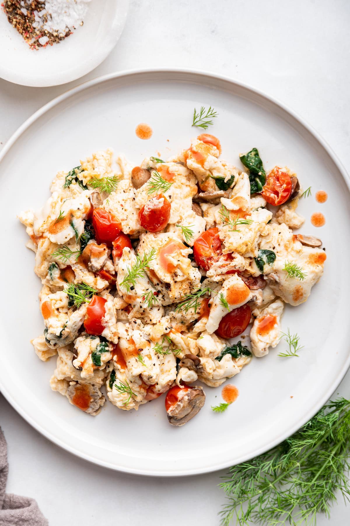 Scrambled egg whites with fresh herbs and cherry tomatoes on a plate.