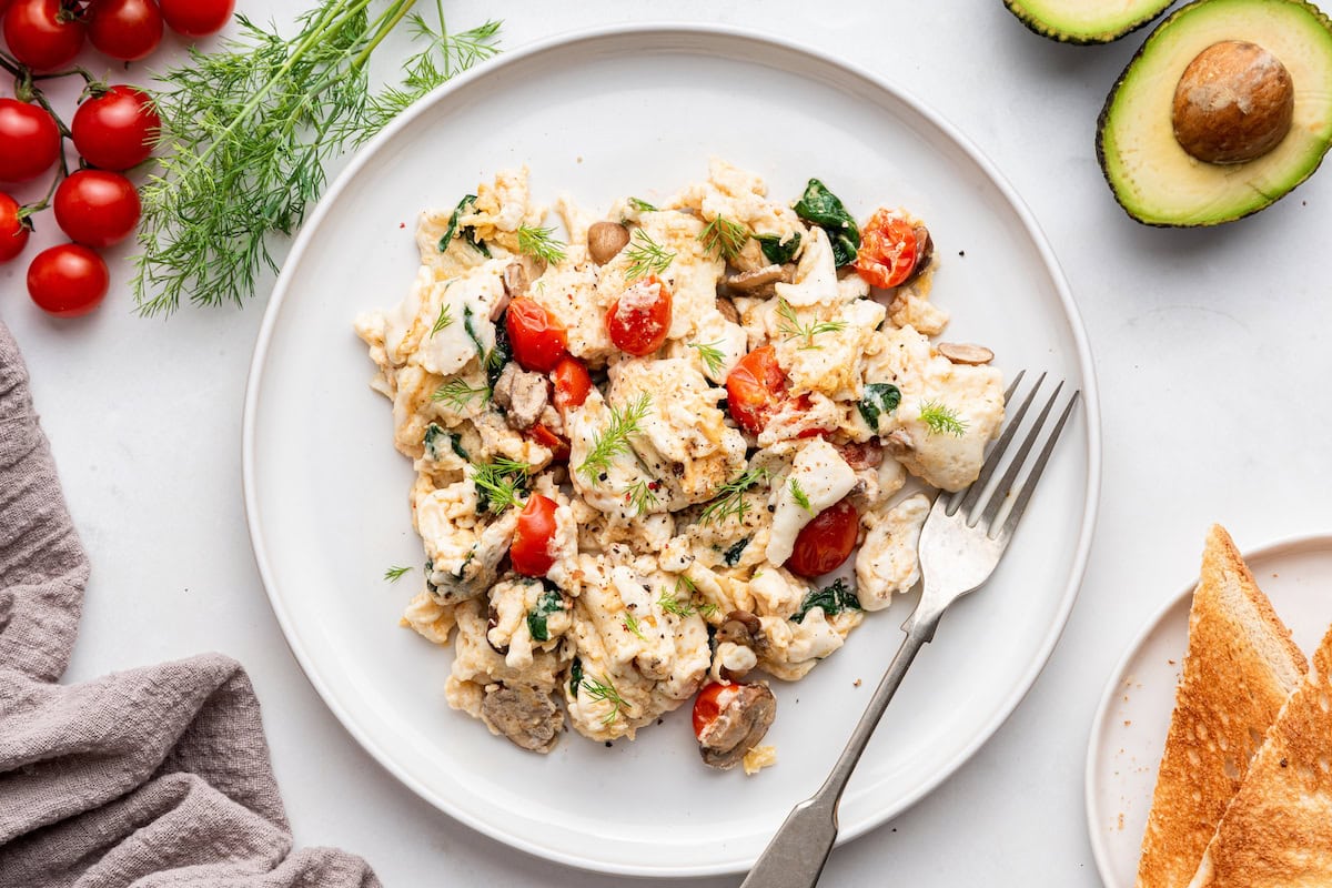 Scrambled egg whites with fresh herbs and cherry tomatoes on a plate.