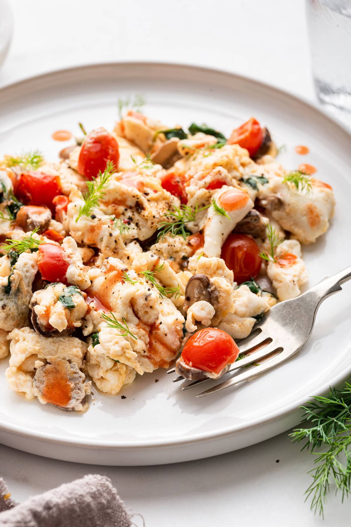 Scrambled egg whites with fresh herbs and cherry tomatoes on a plate.