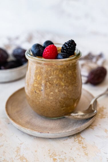 A glass of vanilla overnight oats topped with fresh berries.