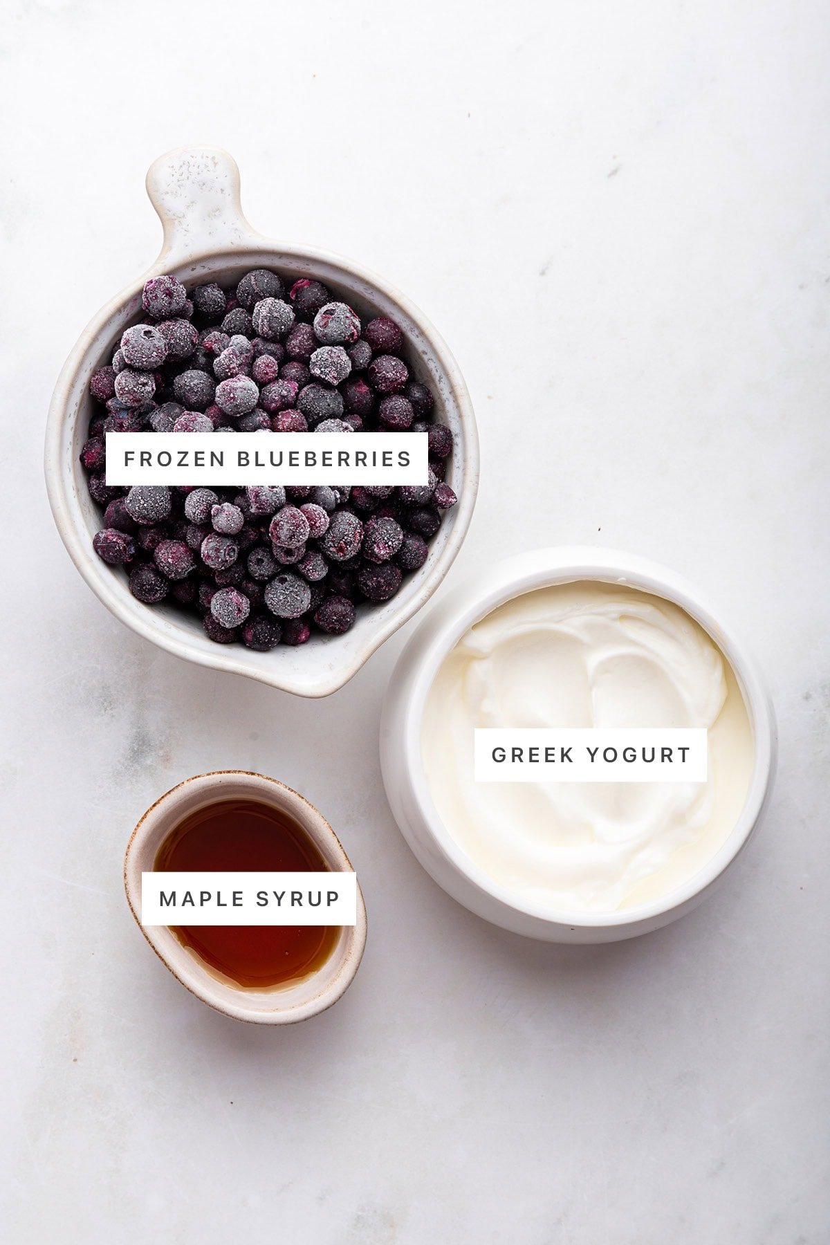 Ingredients measured out to make 3-Ingredient Blueberry Frozen Yogurt: frozen blueberries, Greek yogurt and maple syrup.