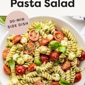 Pesto Pasta Salad with mozzarella and cherry tomatoes in a bowl.
