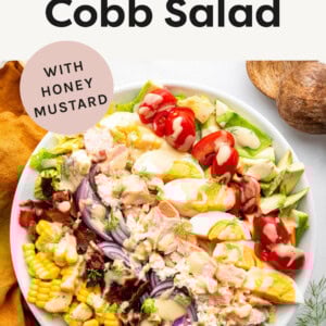 Salmon Cobb Salad in a serving bowl drizzled with honey mustard.