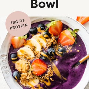 Smoothie bowl topped with berries, banana, seeds and nut butter.