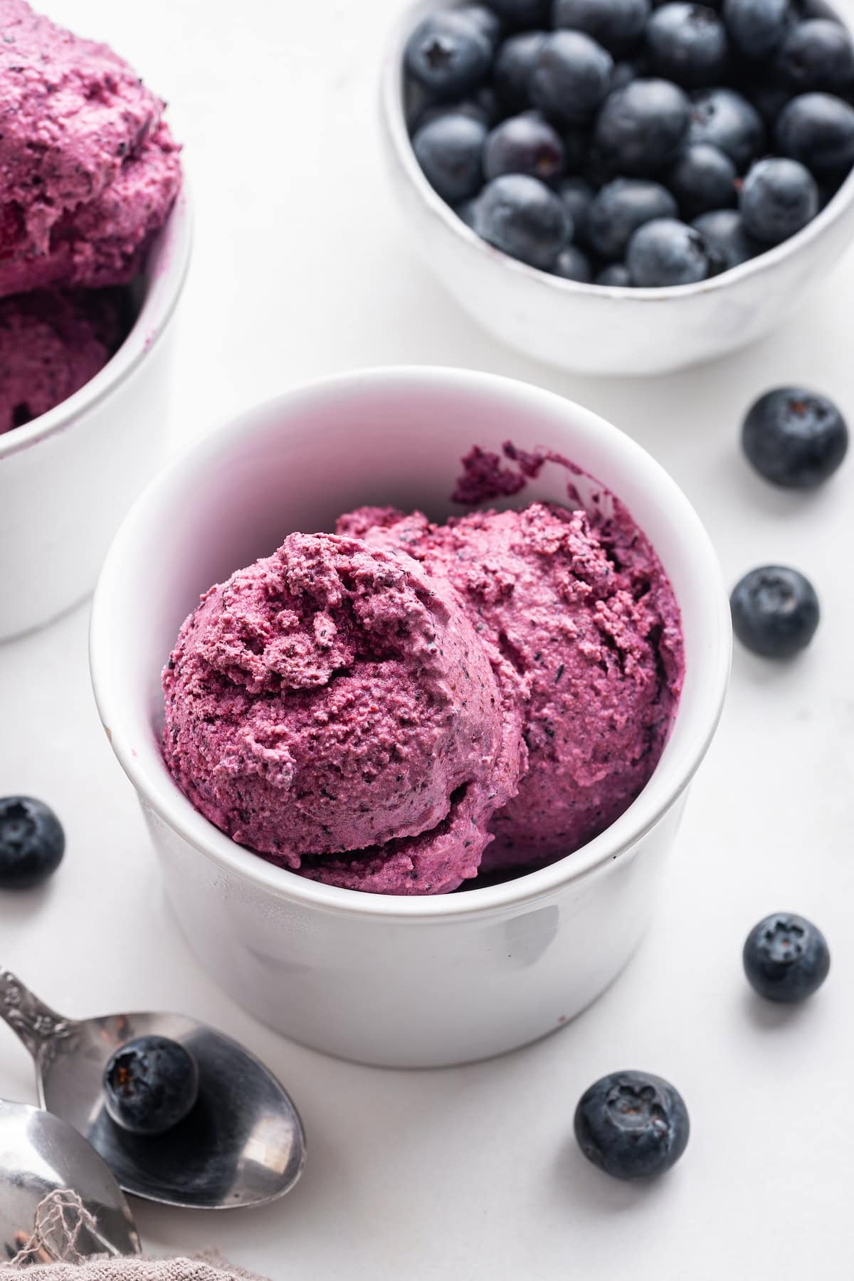 Blueberry frozen yogurt in a small bowl near fresh blueberries.