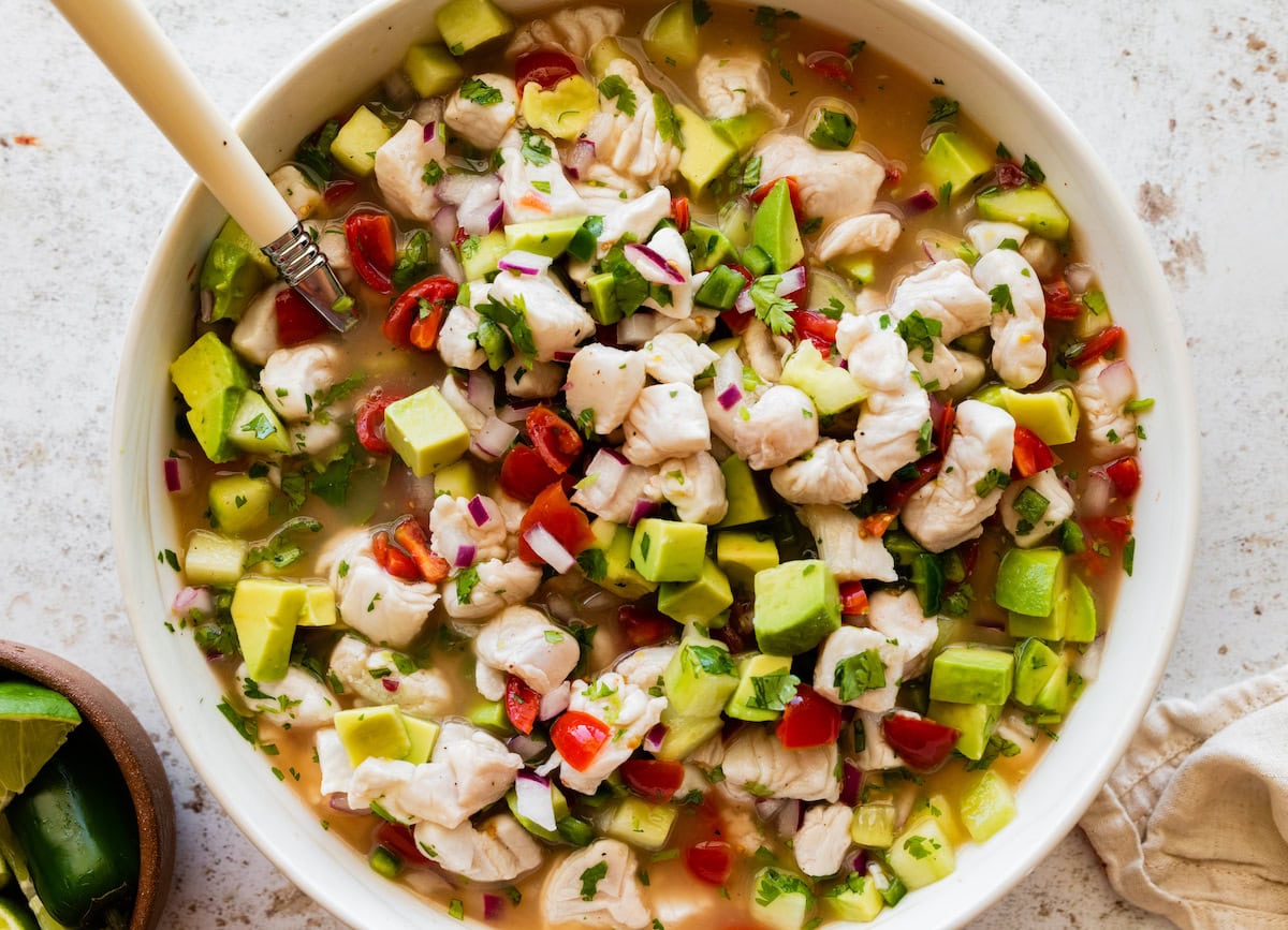 A large mixing bowl of ceviche with fresh fish and vegetables.