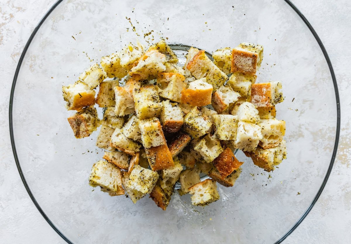 Seasoned croutons in a large glass bowl.