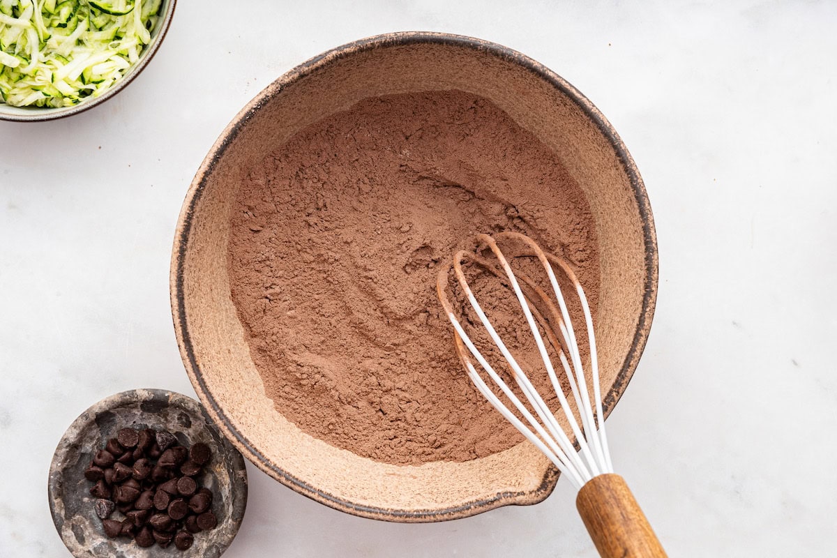 Cocoa powder in a large mixing bowl with a whisk.
