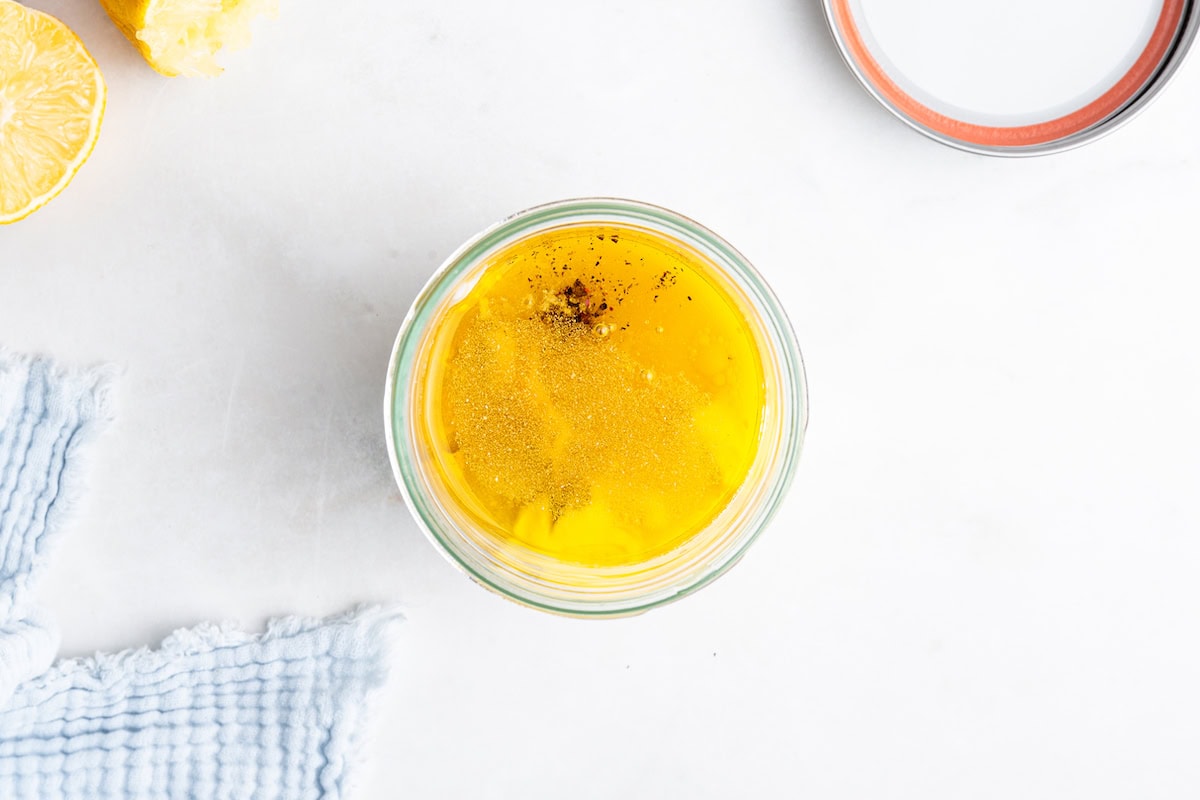 Dijon mustard, apple cider vinegar, lemon juice, and more in a glass jar before being mixed.