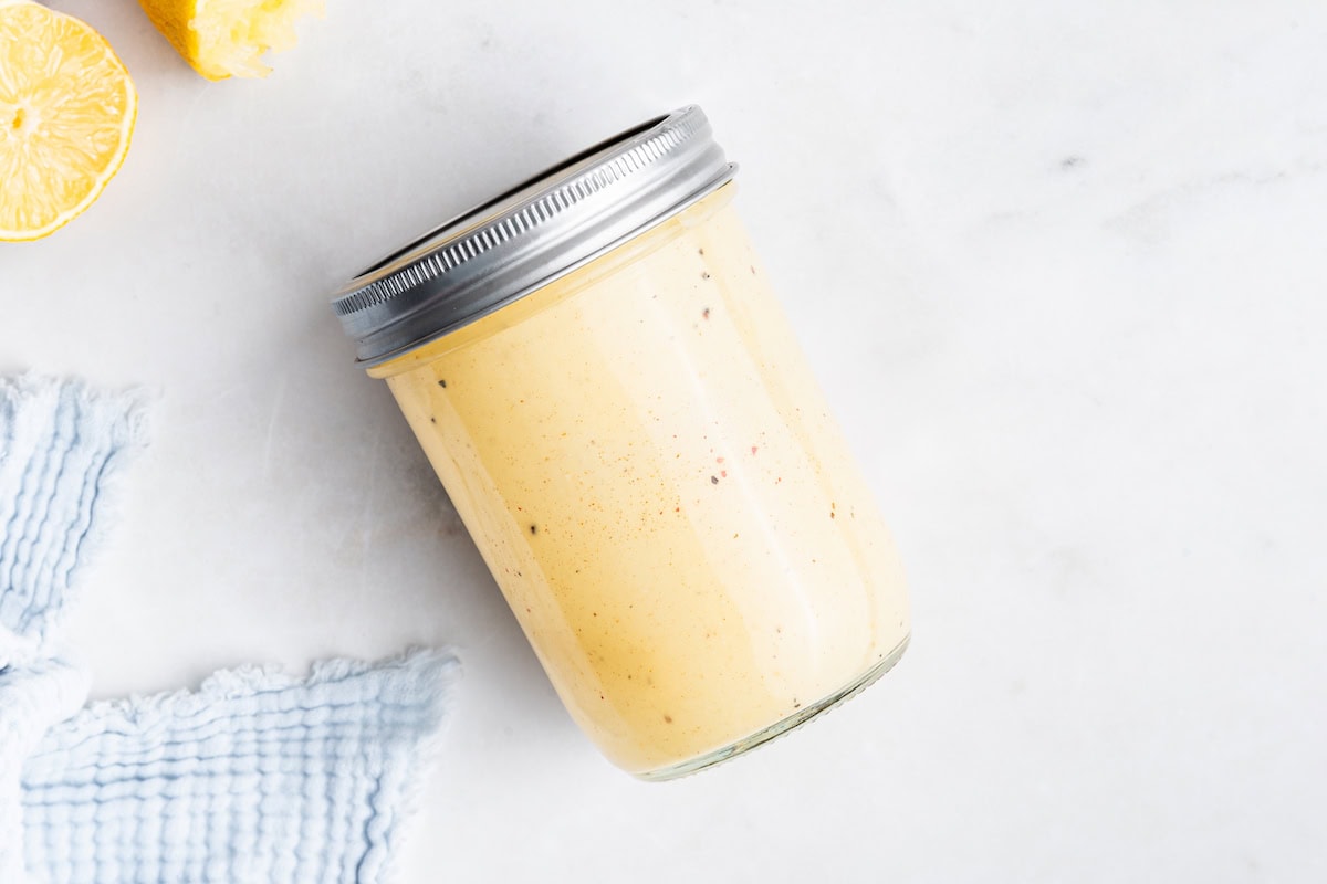 Creamy honey mustard dressing in a closed mason jar.