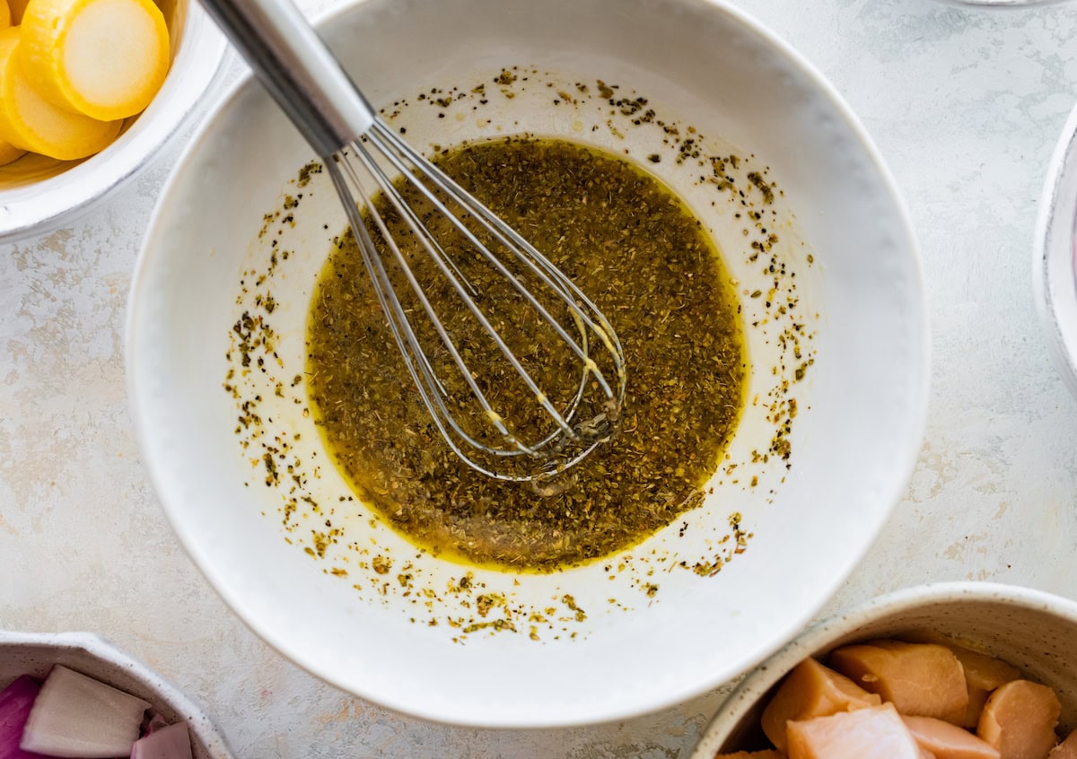 A marinade used for grilled chicken kabobs in a mixing bowl with a metal whisk.