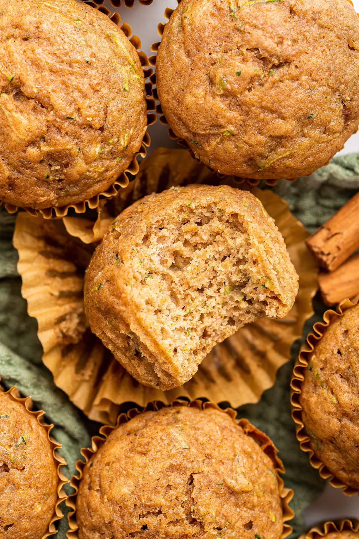 A zucchini muffin with a large bite taken out of it near other zucchini muffins.