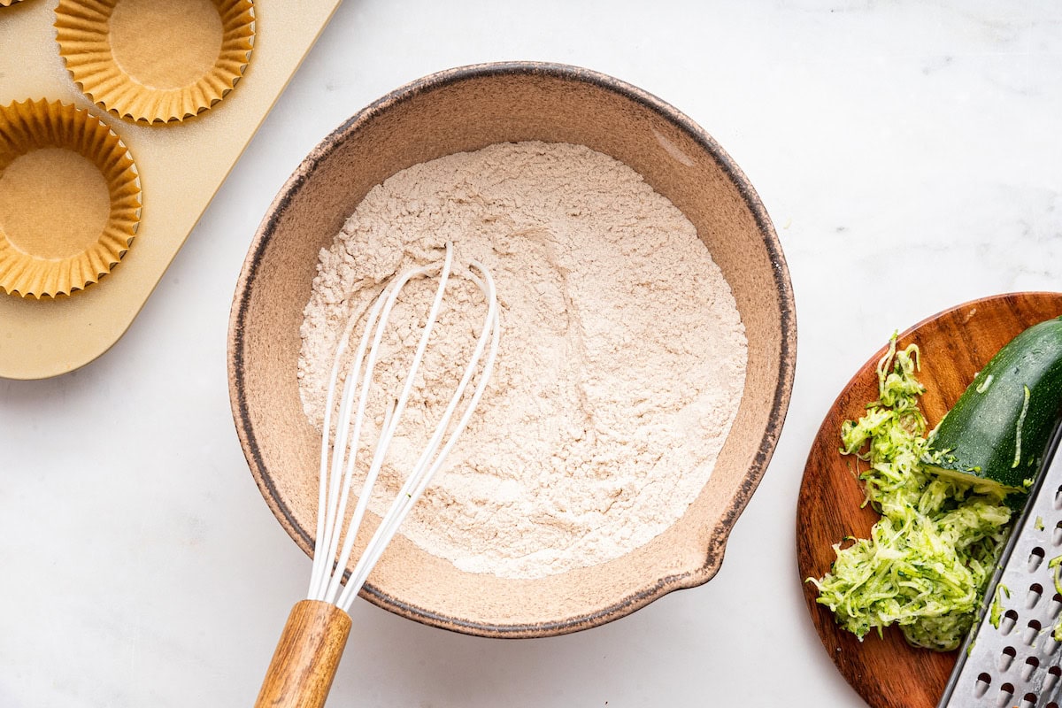 A large mixing bowl of flour and a whisk.