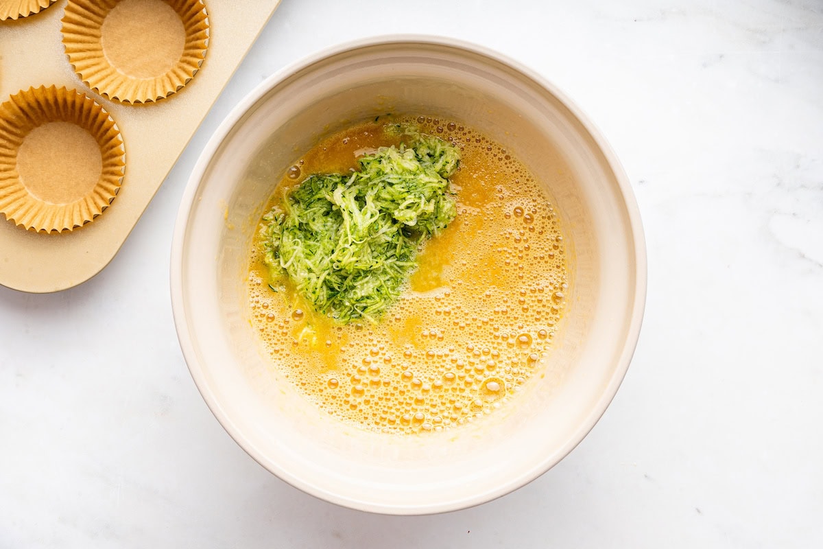 A large mixing bowl of shredded zucchini with eggs.