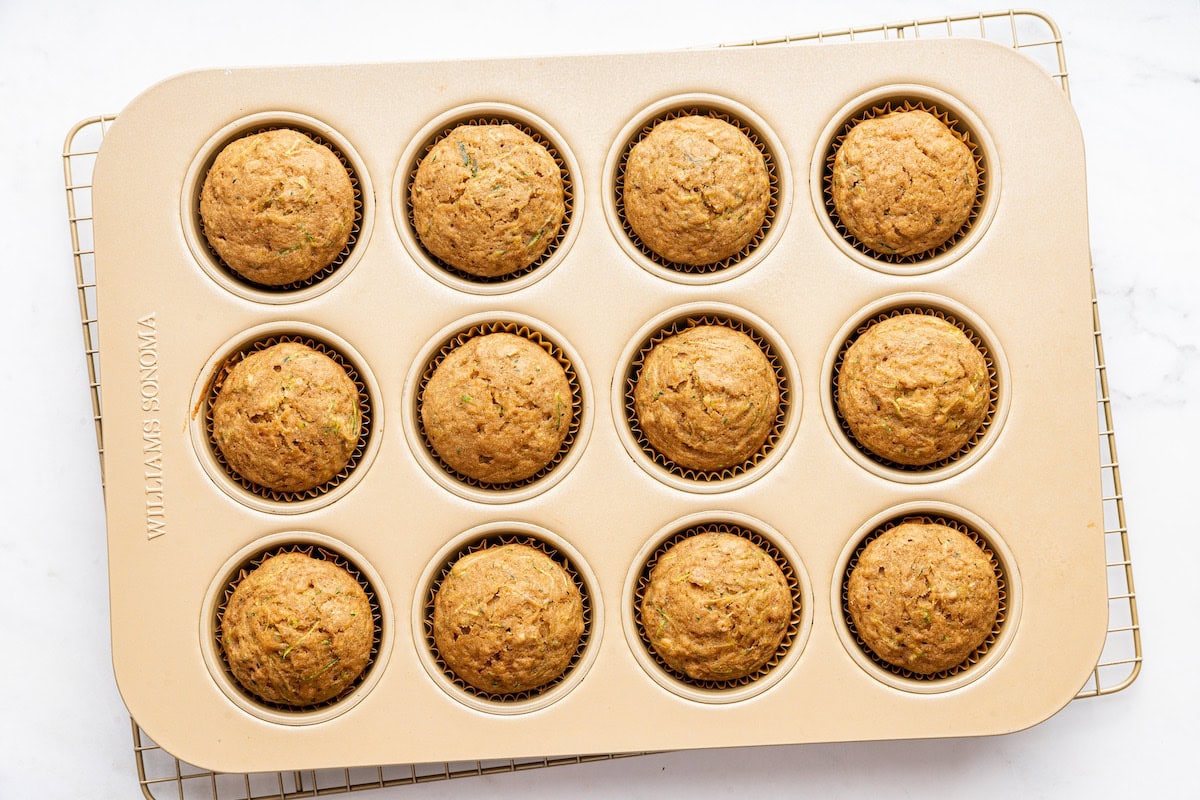 Twelve zucchini muffins in a muffin tin after being baked.