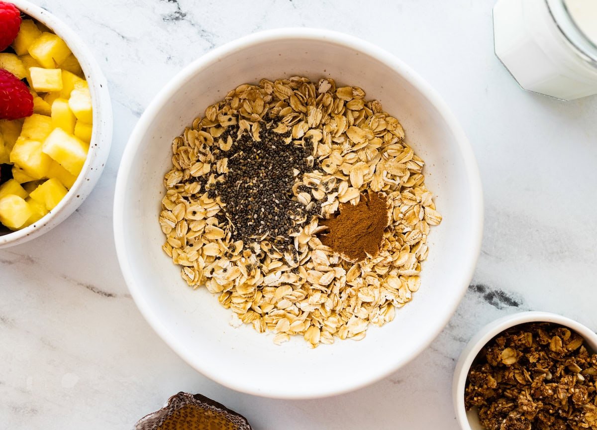 A large white bowl of rolled oats, chia seeds, and cinnamon.