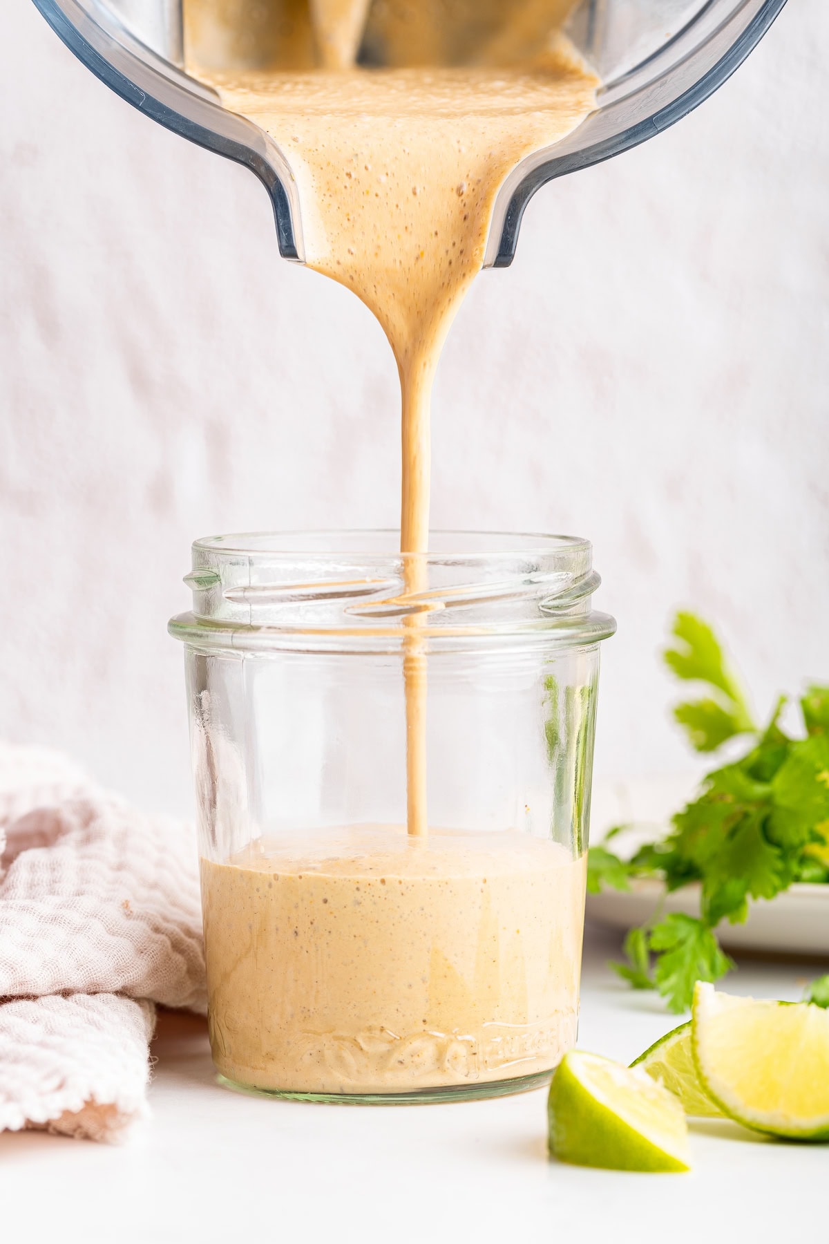 The creamy southwest dressing being poured into a glass jar from a blender.