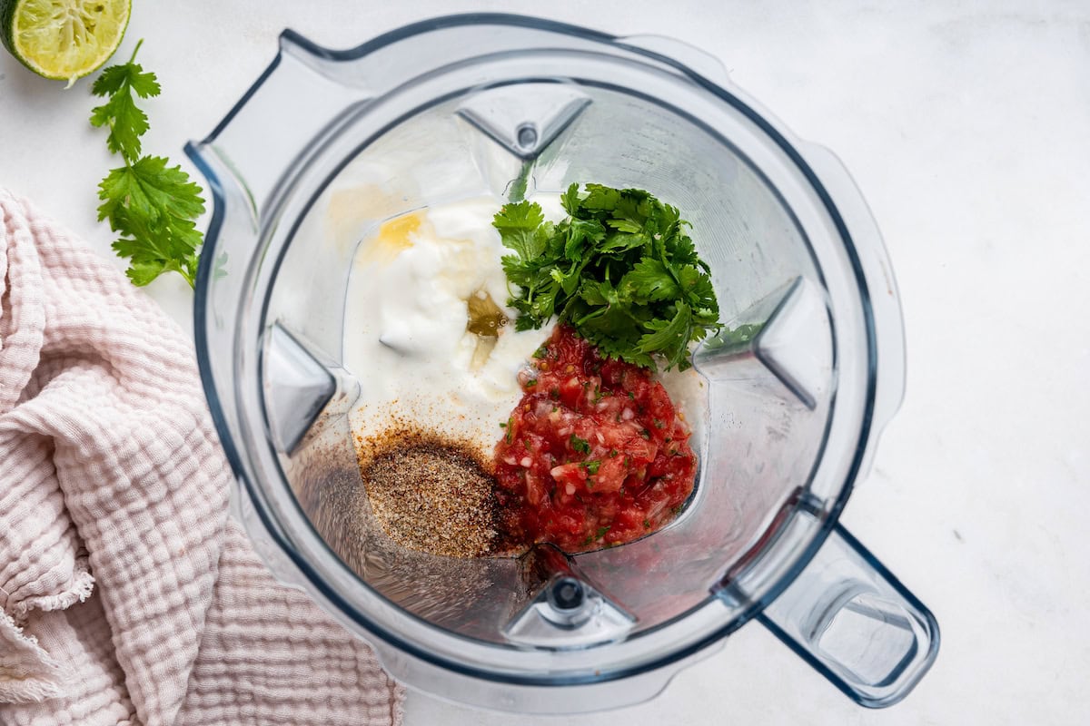 Ingredients for the creamy southwest dressing in the base of a blender: salsa, yogurt, cilantro, spices and lime juice.