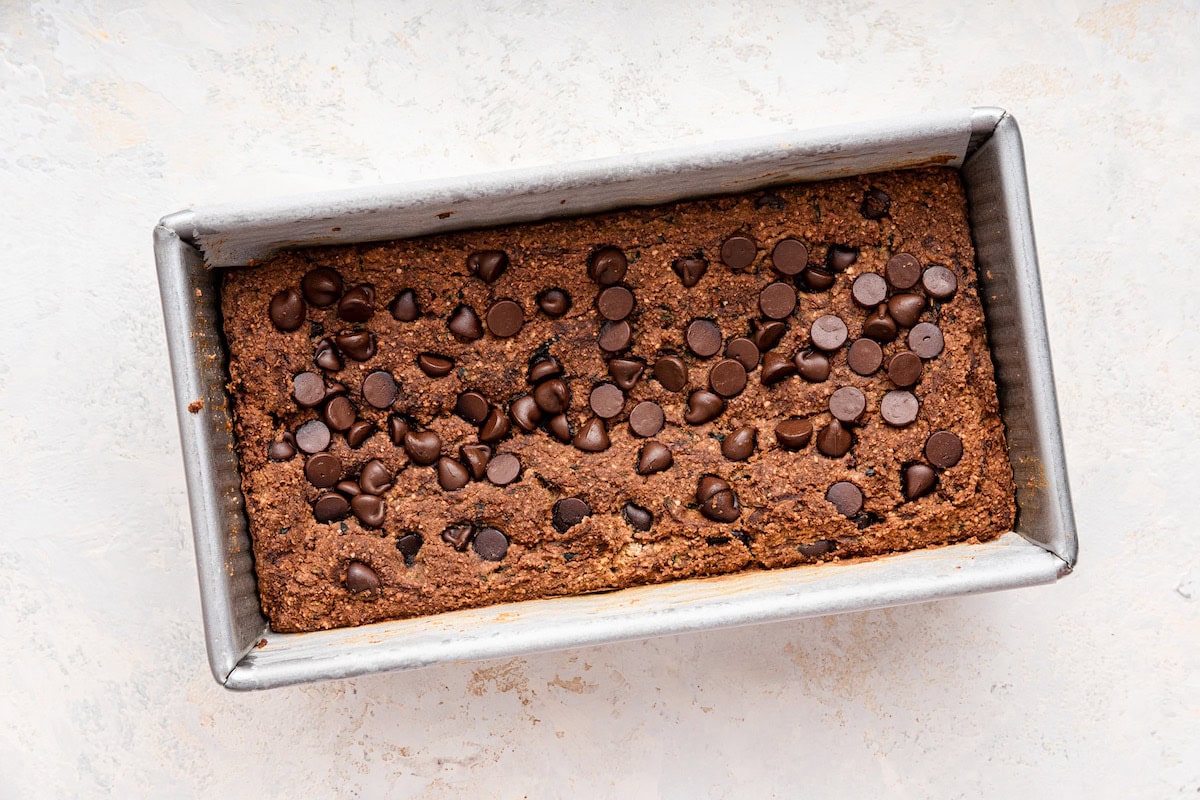Vegan zucchini bread topped with chocolate chips in a bread pan after being baked.