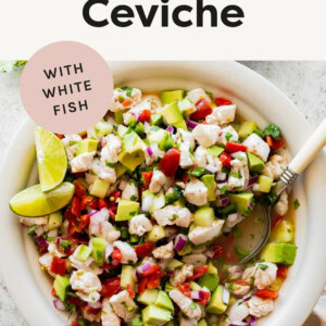 Fish ceviche in a bowl garnished with lime wedges. A serving spoon is in the bowl.