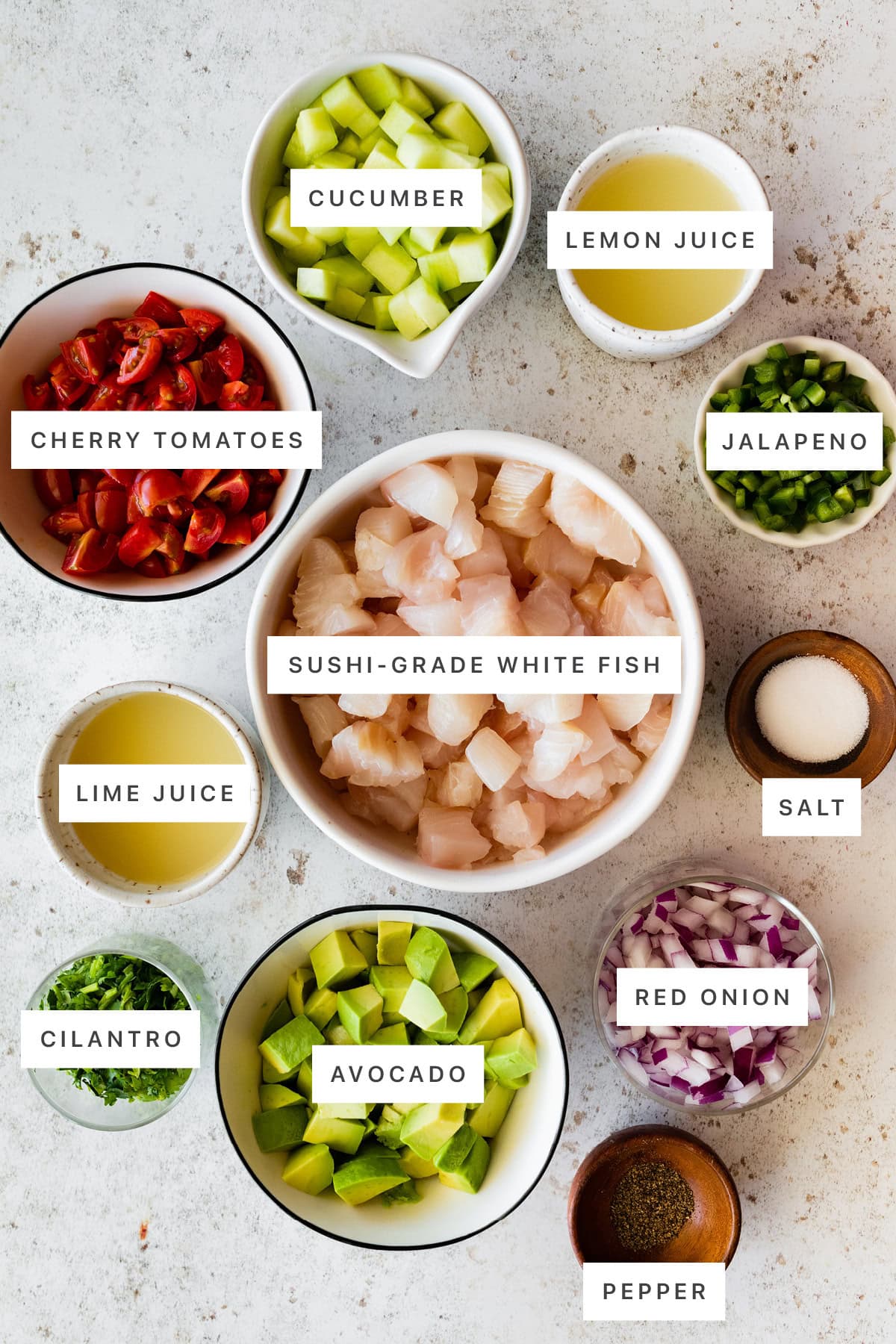 Ingredients measured out to make Easy Ceviche: cucumber, lemon juice, jalapeno, cherry tomatoes, sushi-grade white fish, salt, lime juice, cilantro, avocado, red onion and pepper.