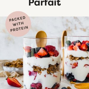 Two Fruit and Yogurt Parfait in glasses with wood spoons.
