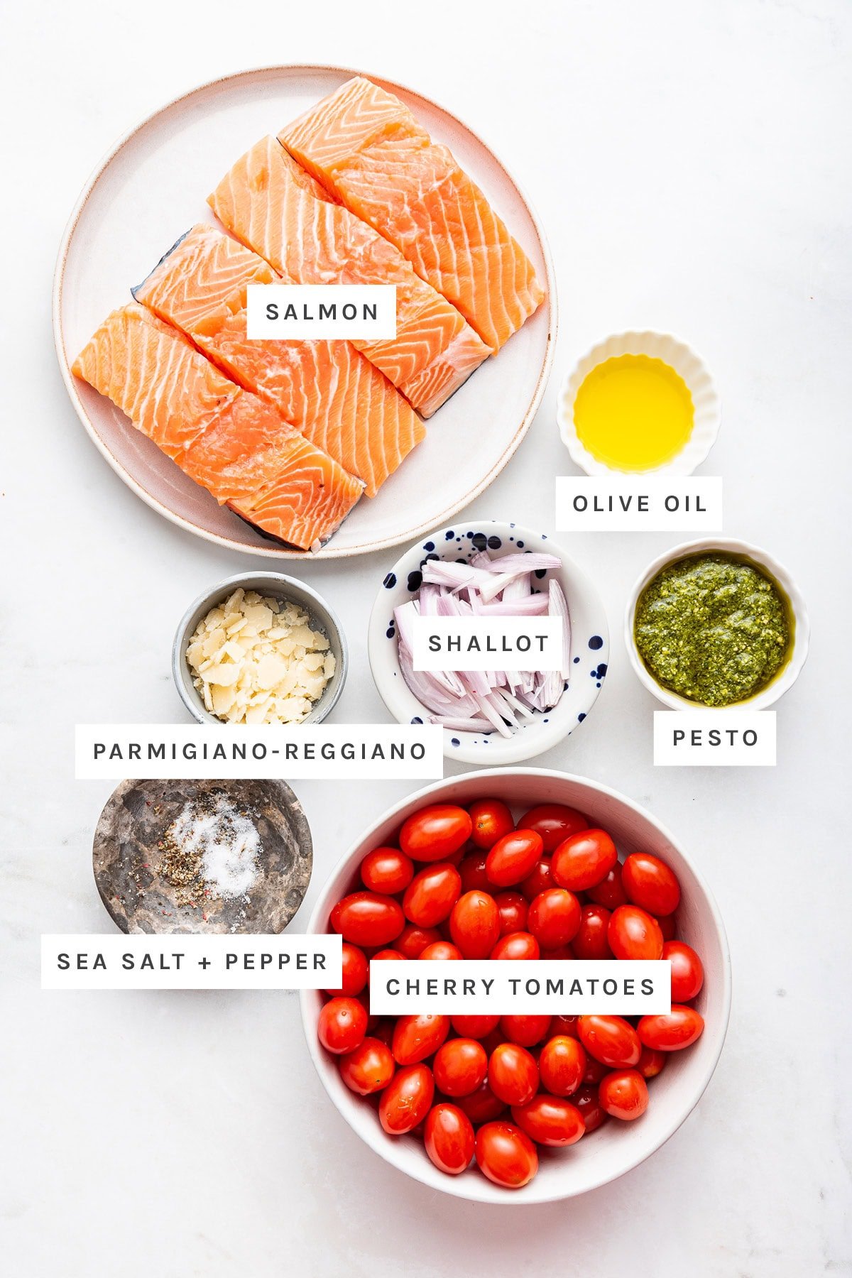 Ingredients measured out to make Pesto Salmon: salmon, olive oil, shallot, pesto, parmigiano-reggiano, sea salt, pepper and cherry tomatoes.