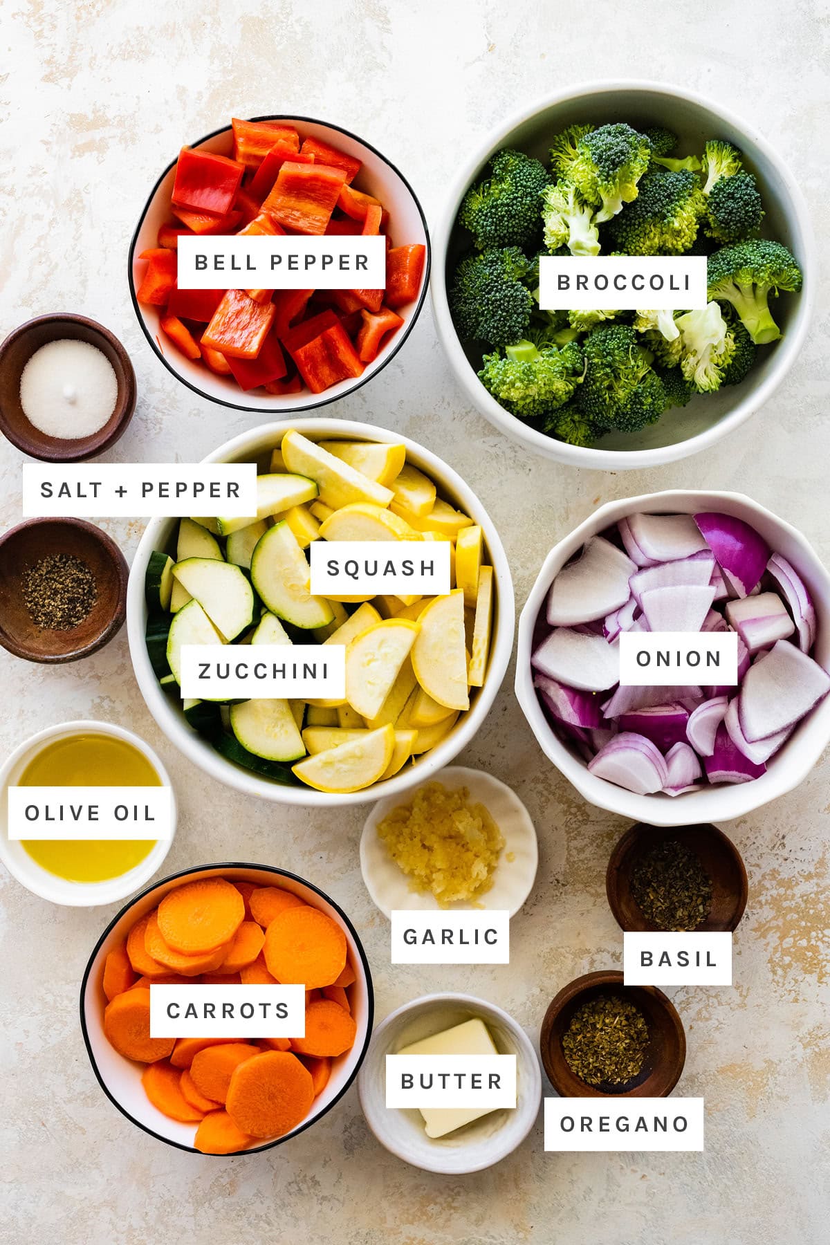 Ingredients measured out to make Sautéed Vegetables: bell pepper, broccoli, salt, pepper, squash, zucchini, onion, olive oil, garlic, carrots, butter, basil and oregano.
