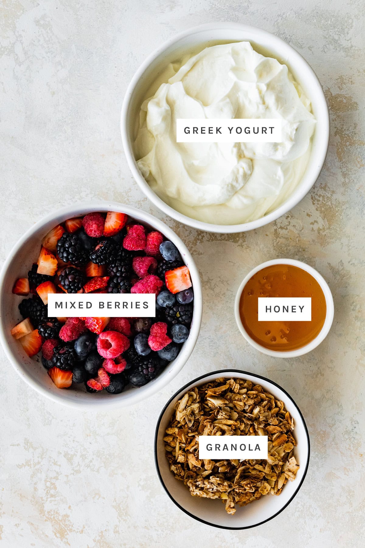 Ingredients measured out to make Fruit and Yogurt Parfait: Greek yogurt, mixed berries, honey and granola.