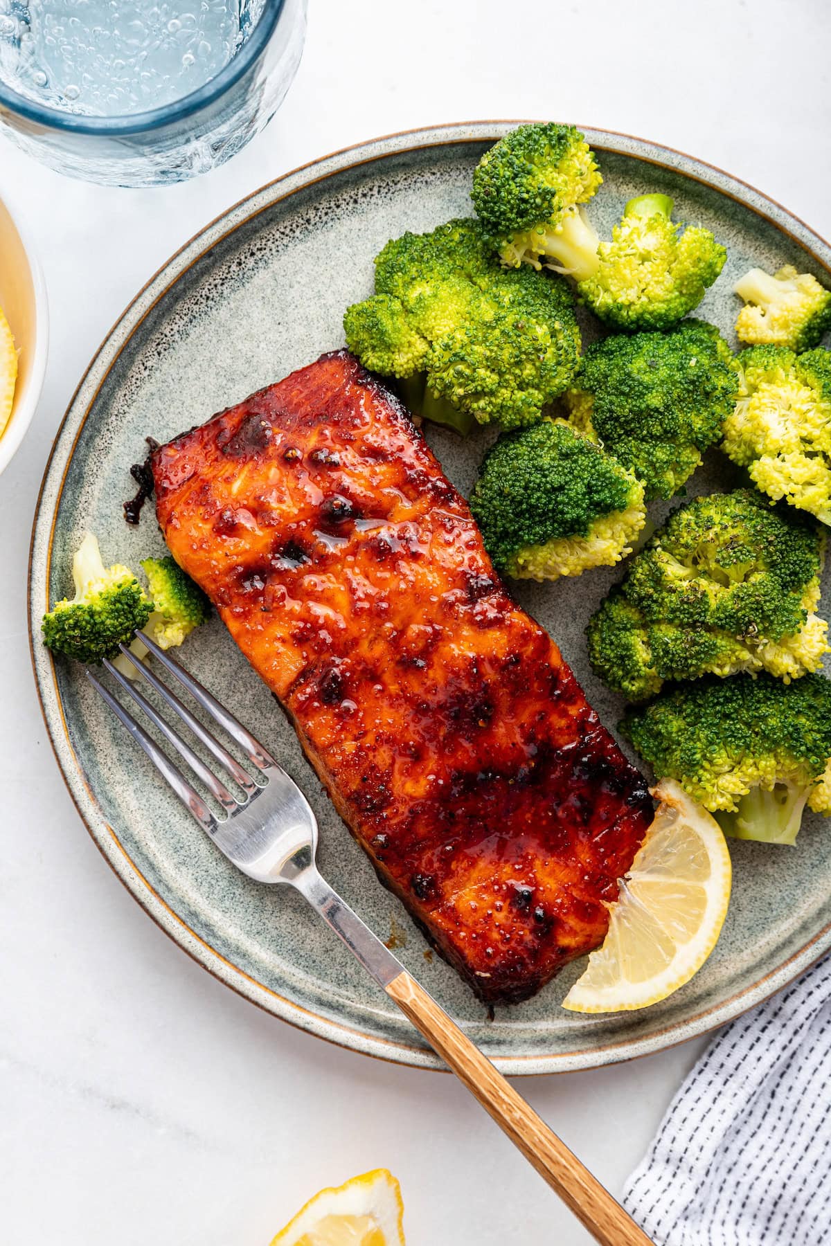 A date glazed salmon filet on a plate with a side of broccoli.