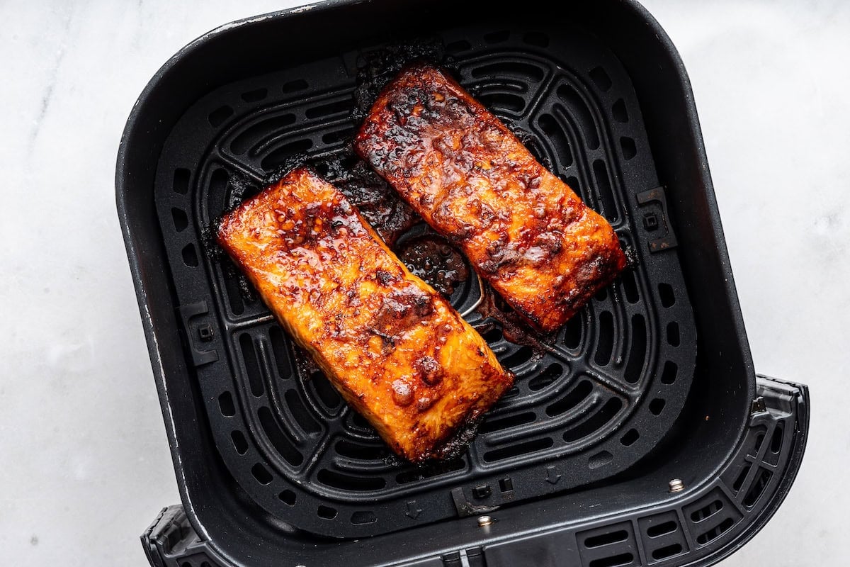 Two date glazed salmon filets in an air fryer basket.