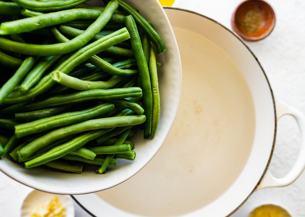 Green beans are being added to a large pot of water.