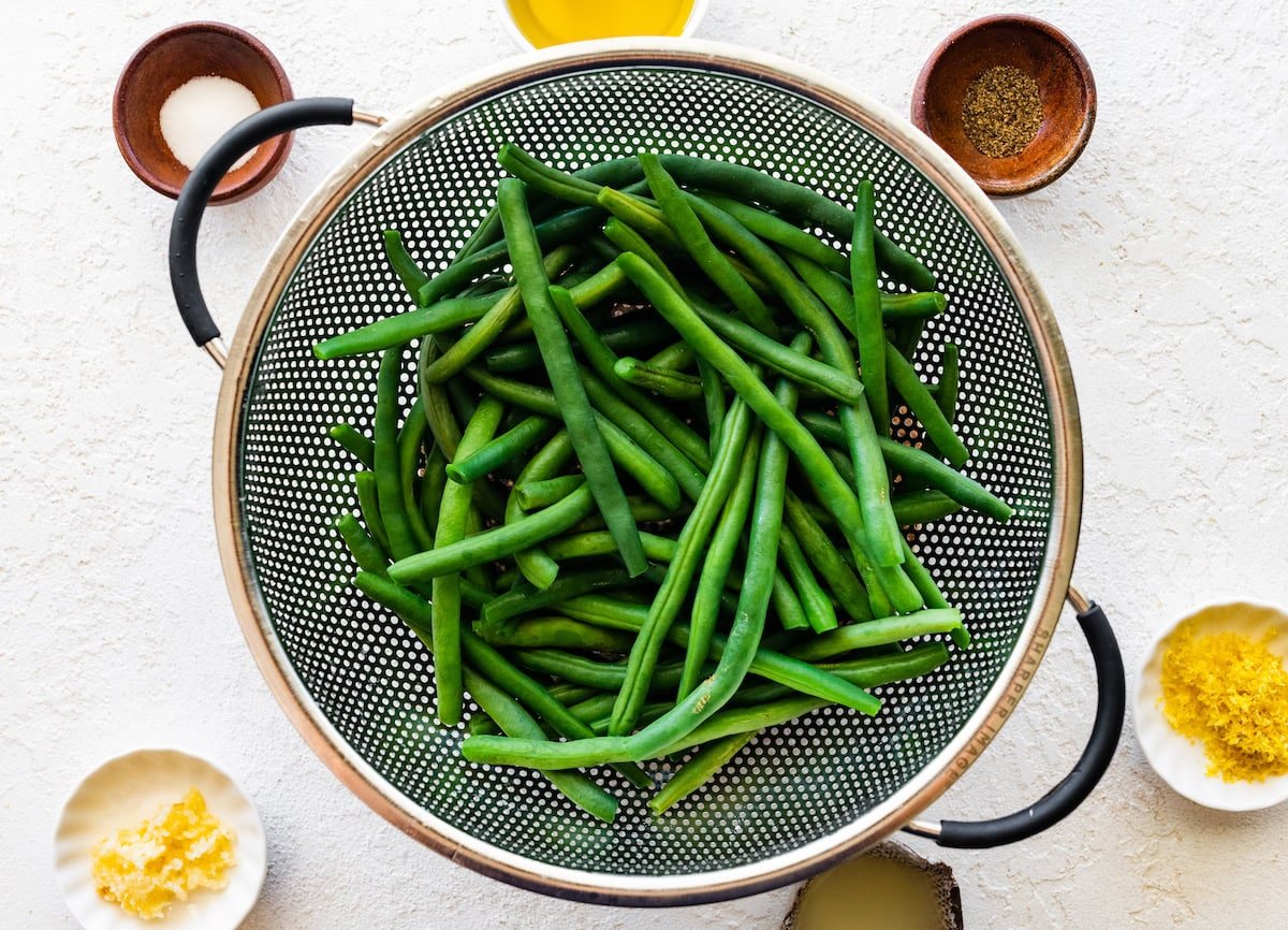 Green beans in a metal strainer after being cooked in a pot of water.