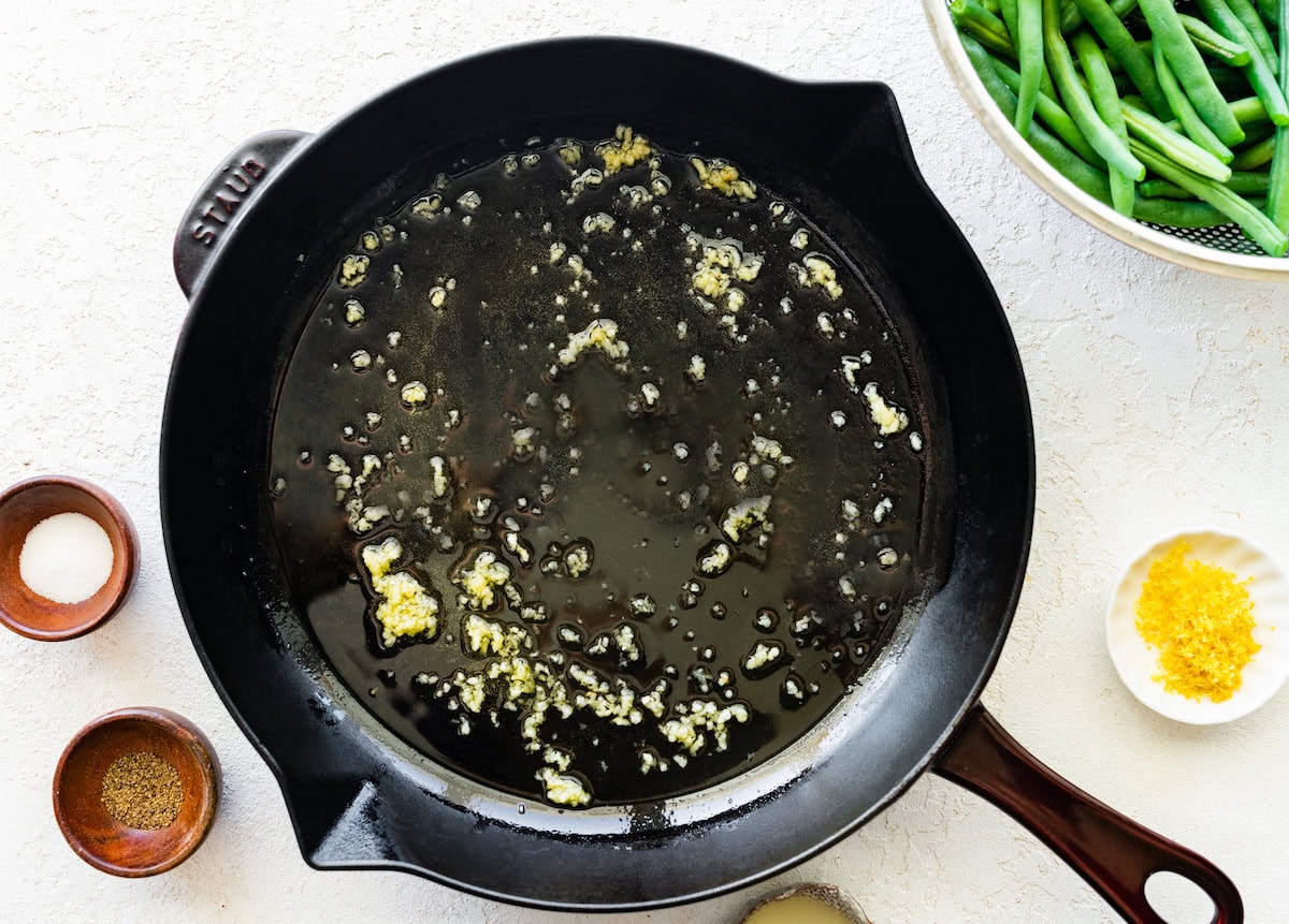 A cast iron skillet with minced garlic.