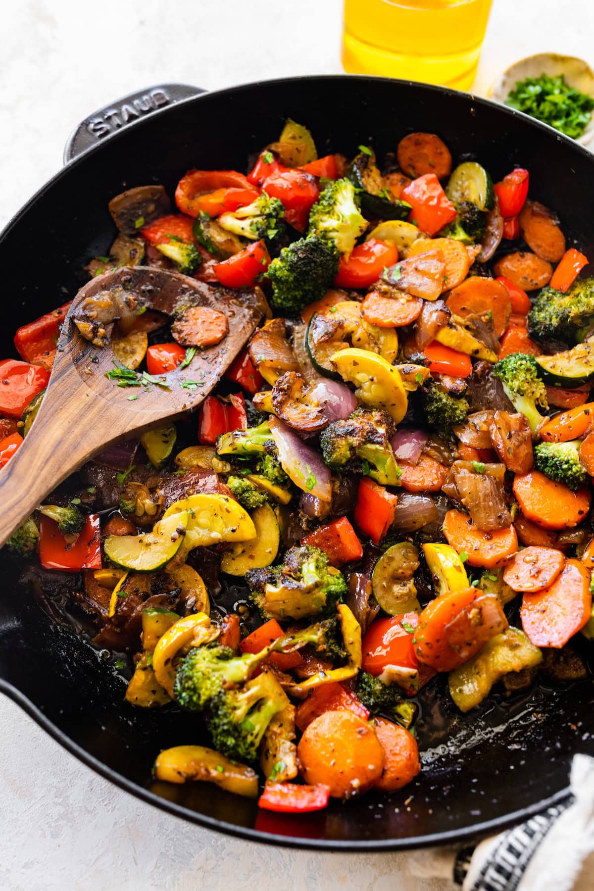 A cast iron skillet of sautéed vegetables including broccoli, carrots, onion, tomatoes, zucchini, and more.