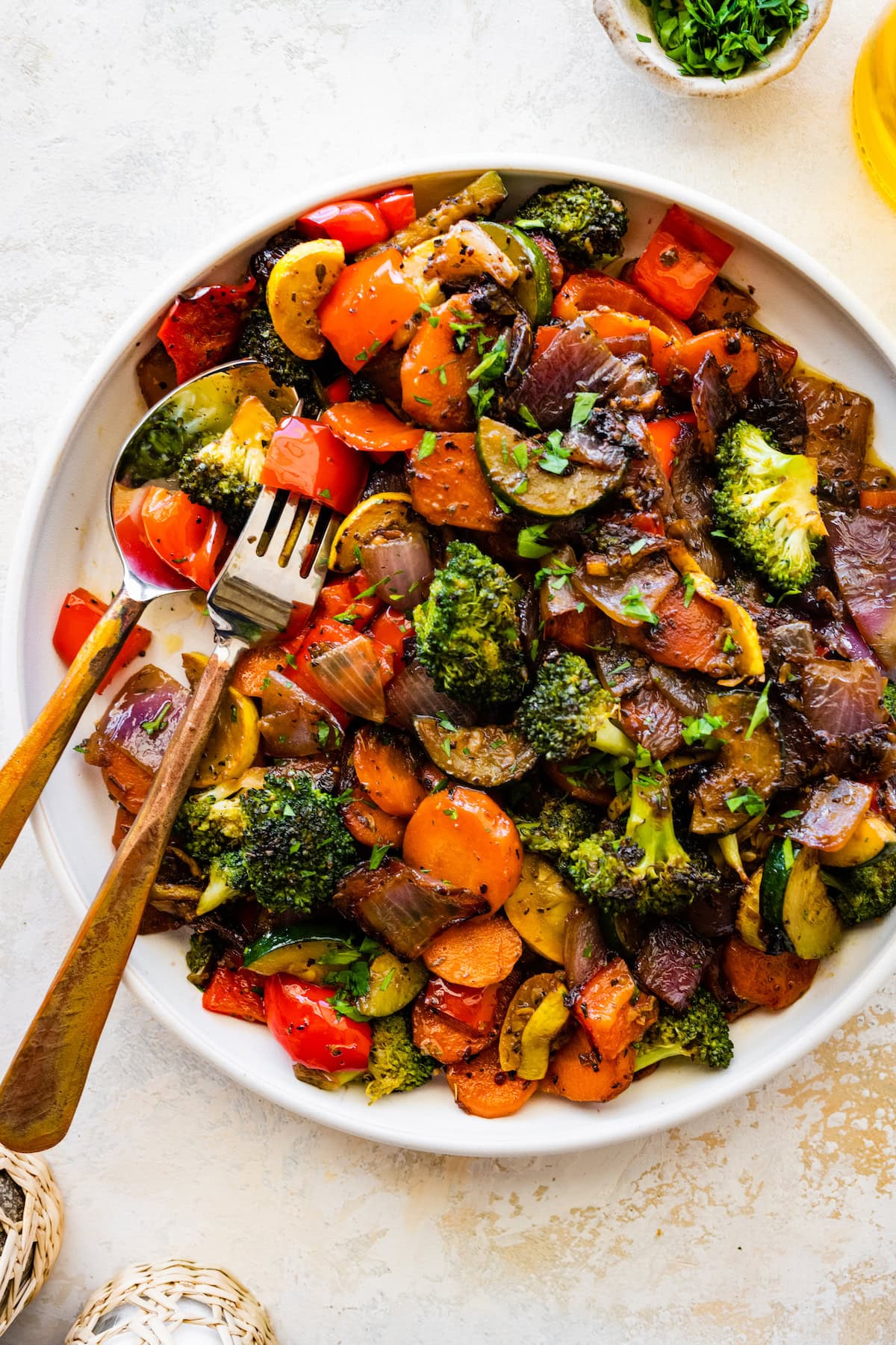 A large plate of sautéed vegetables including broccoli, carrots, onion, tomatoes, zucchini, and more.