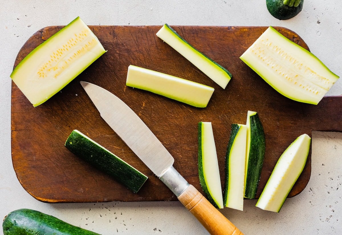 A cutting board with sliced zucchini and a knife.