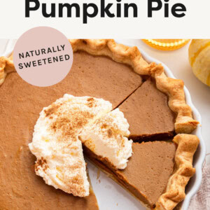 Healthy Pumpkin Pie topped with some whipped cream and cinnamon. A few slices are cut from the pie.