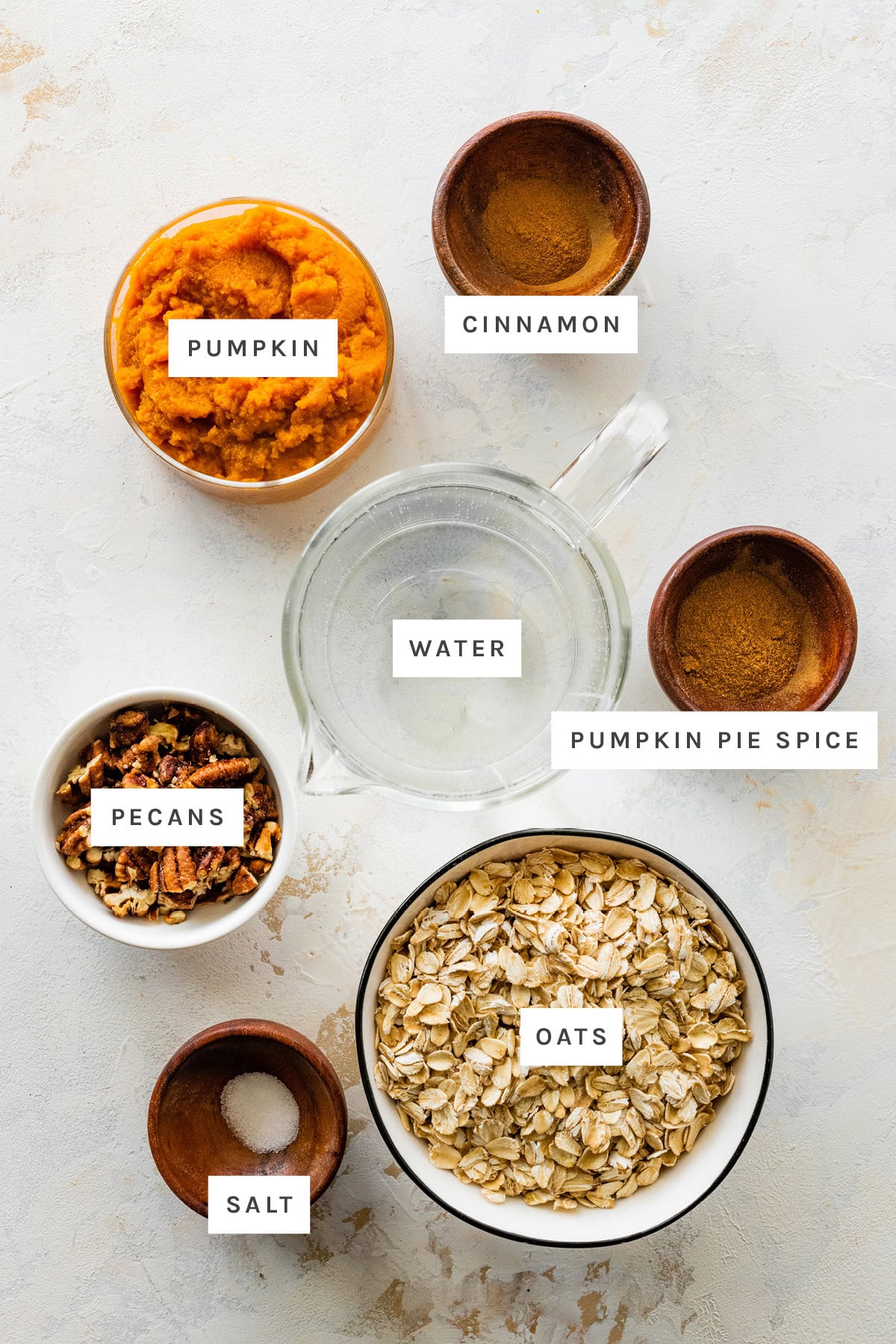 Ingredients measured out to make Pumpkin Oatmeal: pumpkin, cinnamon, water, pumpkin pie spice, pecans, oats and salt.