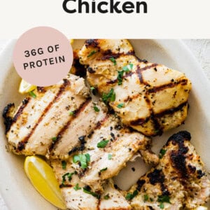 Grilled Yogurt Marinated Chicken on a platter with lemon and herbs.